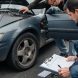 Inspection réaliste d’une voiture d’occasion sur un parking européen, avec documents administratifs et ambiance automobile.