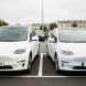 Deux voitures électriques, une compacte fabriquée en Chine et une citadine européenne, stationnées côte à côte sur un parking français avec des bornes de recharge en arrière-plan.